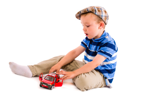 Little boy plays with red toy car, white background