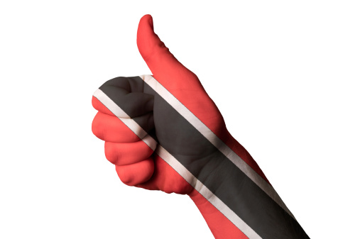 Hand with thumb up gesture in colored trinidad tobago national flag as symbol of excellence, achievement, good, - for tourism and touristic advertising, positive political, cultural, social management of country