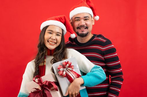 Happy smiling couple asian person holding gift box over red background.