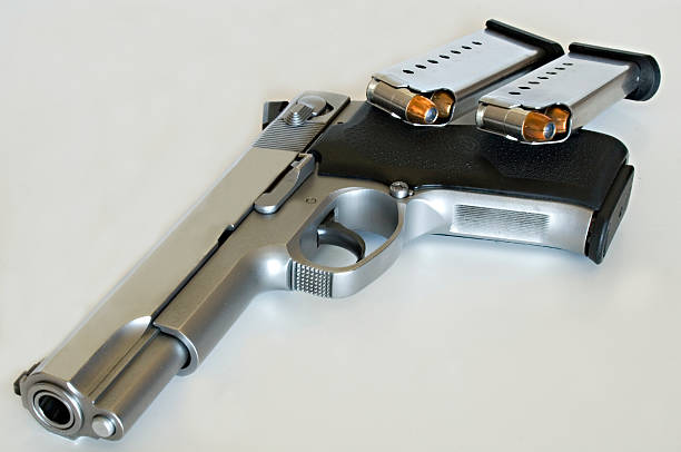.45 Caliber Gun .45 Caliber Gun with two ammunition clips along the grip of the gun. forty five caliber handgun stock pictures, royalty-free photos & images