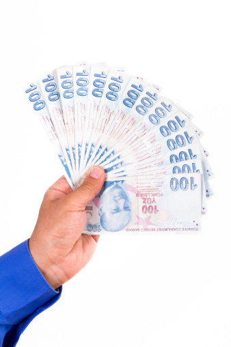 Businessman hand holding and counting one hundred Turkish liras banknotes, isolated on white background.