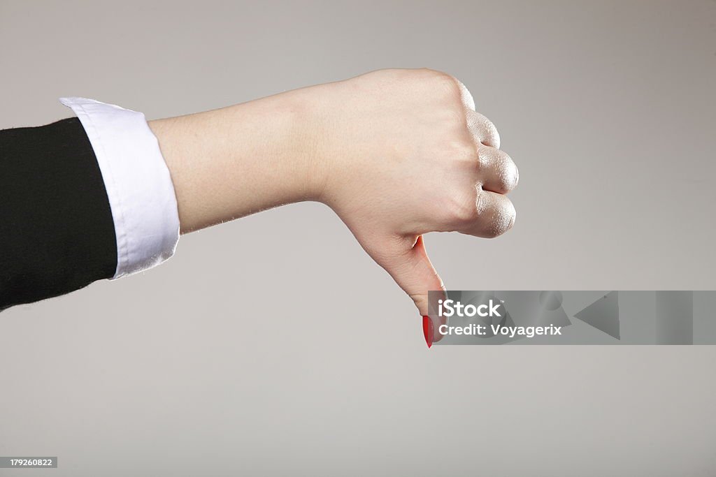 Female hand signaling thumb down Business woman's thumb down hand sign gray background Adult Stock Photo