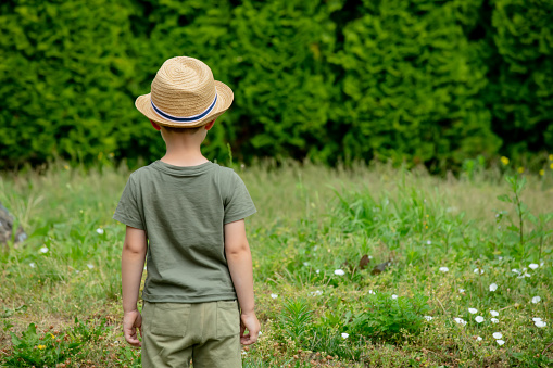 Little autist preschool boy in hat play in garden
