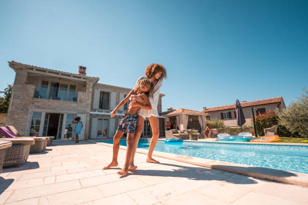 istock Young Girl Playfully Throws Brother into Pool 1792611000