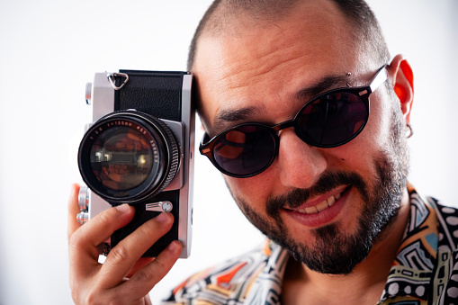 Banner size shot of a bearded man holding an old vintage photo camera with copy space aside.