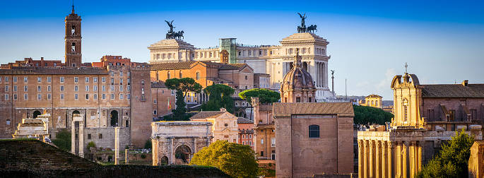 A splendid cityscape of the Roman Forum seen from the gardens of the Palatine Hill, in the heart of the Eternal City. On the horizon the Altare della Patria National Monument and the Capitoline Hill with the Campidoglio, or Roman Capitol. Below on the center, the triumphal arch of Septimius Severus and on the right the colonnade of the Temple of the Divine Julius. The Palatine Hill, one of the seven ancient hills of Rome, it is the place where important imperial palaces stood, such as the Domus Flavia and the Domus Augustana. In 1980 the historic center of Rome was declared a World Heritage Site by Unesco. Image in original 65:24 ratio and high definition format.