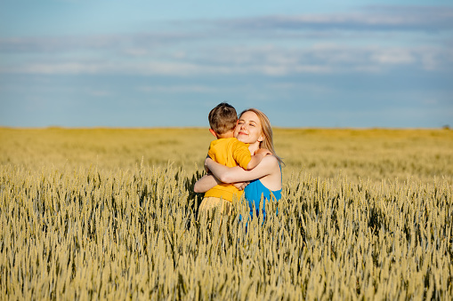 Mother with son in ukrainian national colors in wheat field