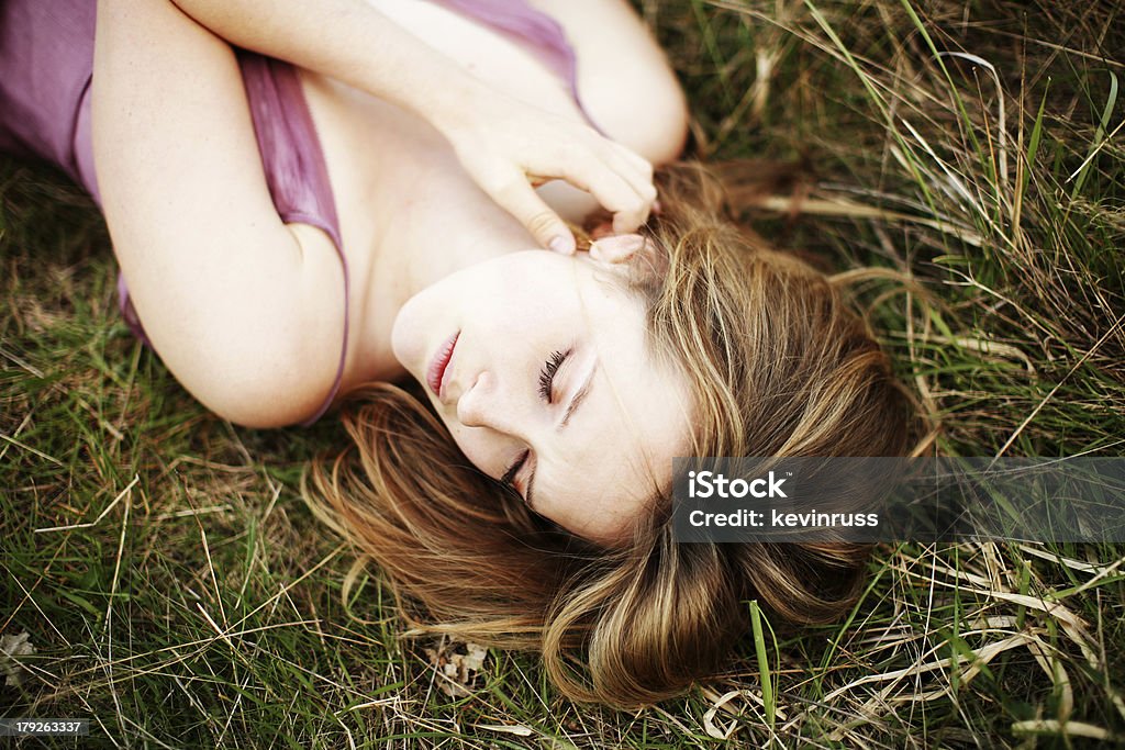 Blonde femme soulevant et fermé les yeux à grande Plante herbacée - Photo de 20-24 ans libre de droits