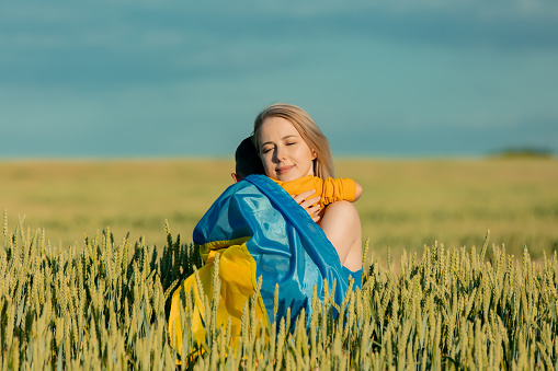 Mother with son in ukrainian flag in wheat field