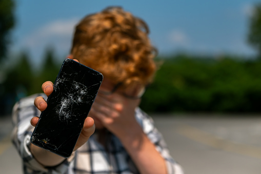 Sad boy with cracked smart phone