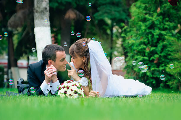 istock groom and bride lie on a grass around soap bubbles 179264324