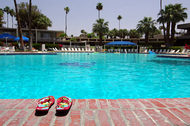 Get Away From It All "Sandals Next To Large Empty Swimming Pool In Palm Springs, California" palm desert pool stock pictures, royalty-free photos & images