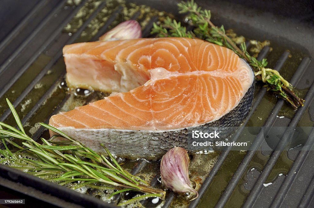 Salmon Salmon steak being fried in a pan with rosemary,thyme and garlic Color Image Stock Photo