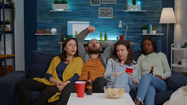 istock Mixed race friends watching funny video on television sitting on sofa 1792662021