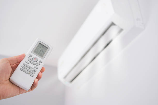 Man's hand using remote control open The air conditioner is cooled to 25 degrees Celsius in his bedroom. Health concepts and energy savings