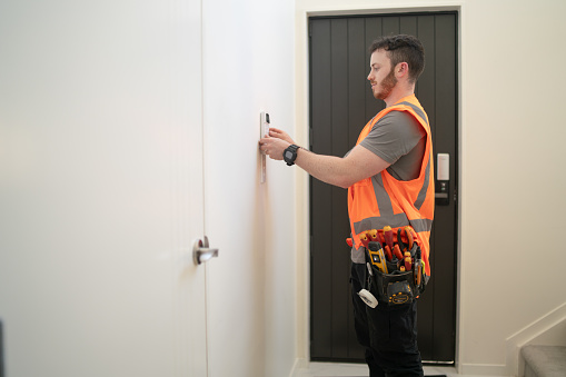 Male electrician checks alarm installed is working