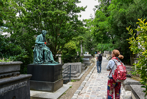 The characteristic and historic cemetery of Pere Lachaise, shot of one of the cobbled paths with tourists intent on observing the tombs of famous people.