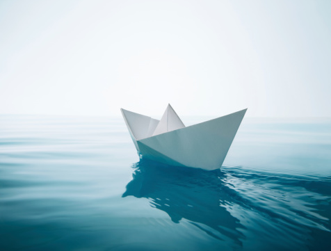 paper boat sailing on water causing waves and ripples