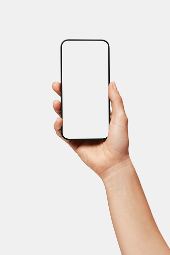 Close-up of woman hand holding modern smartphone iphone. New modern black frameless smartphone mockup with blank white screen. Isolated on white background high-quality studio shot