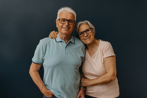 Happy senior couple looking at camera in front of the blue background