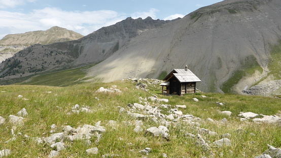 Rocky, grey green mountain landscape with small shepherds hut in the south European Alps