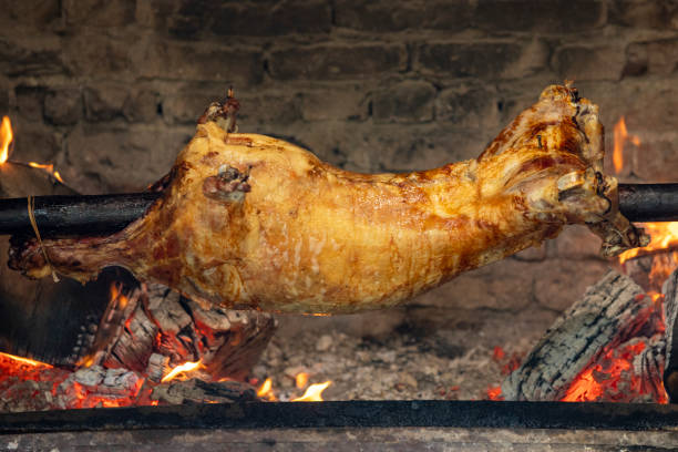 Rotisserie lamb. Whole lamb skewered on a stone stove is cooked over a wood fire. local name kuzu cevirme Rotisserie lamb. Whole lamb skewered on a stone stove is cooked over a wood fire. local name kuzu cevirme smoking meat rotisserie barbecue grill stock pictures, royalty-free photos & images