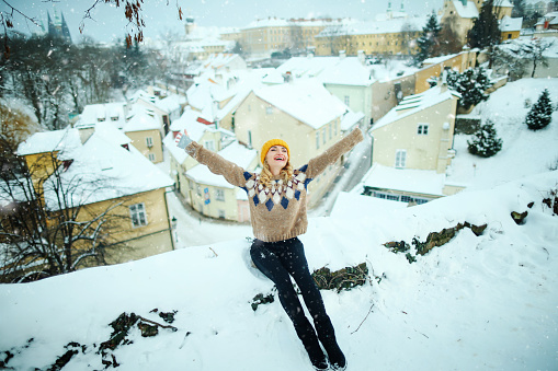Happy woman make fun, enjoy snowfall in beautiful Prague city, enjoying winter holidays
