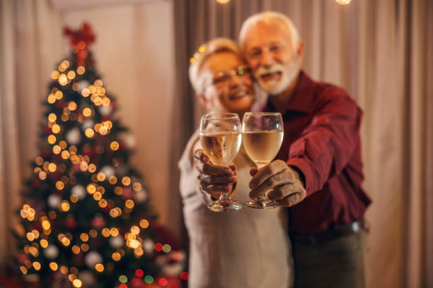 Selective focus of grandparents' hands holding wine and celebrating christmas and new year at home. stock photo