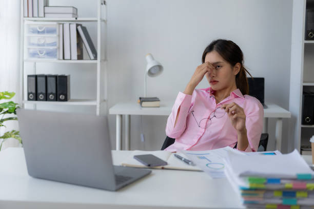 istock Young Asian female worker working with stress pretends to scratch her head because she is very tired working with laptop and documents on the table. 1792700888