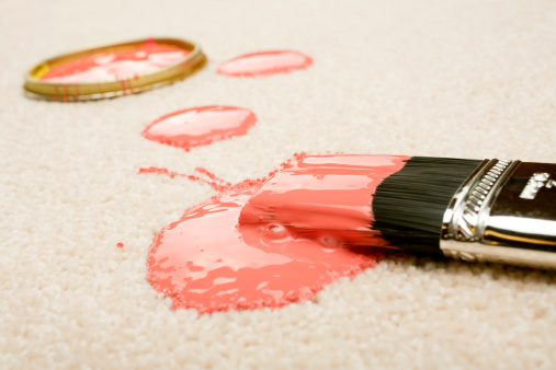 Pink paint spilled on cream coloured carpet with brush.