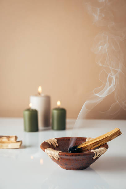 Palo santo burning stick and candles in background stock photo