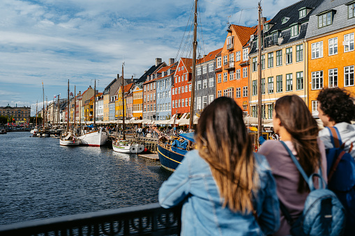 Three young friends enjoying the view in Nyhavn Canal in Copenhagen in Denmark.