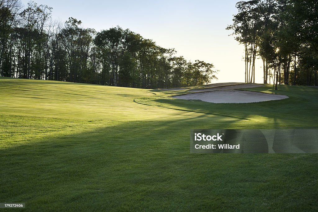 Golf fairway in late afternoon sun Green golf fairway with sand traps in the late afternoon sun Golf Stock Photo