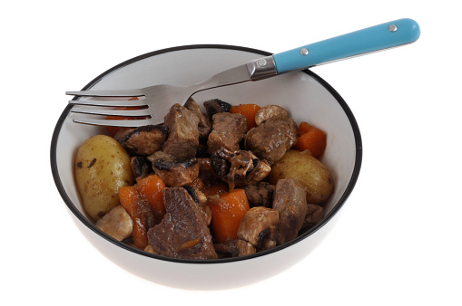Plate of pot-au-feu with a fork close-up on white background