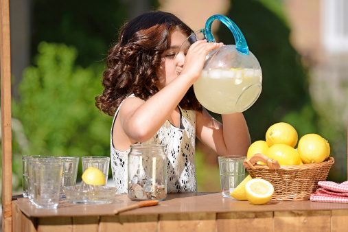 closeup of little girl drinking from lemonade pitcher on a hot summer day