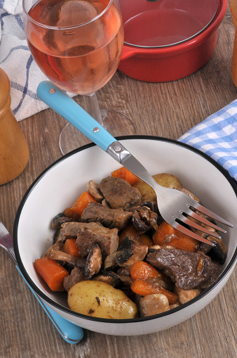 Pot-au-feu served on a plate with a fork and a glass of wine
