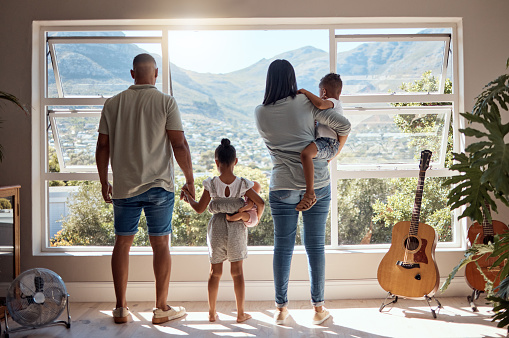 Family, love and window back view in home looking at mountain. Support, trust and baby, mother and father holding hands of girl in house with scenic view, enjoying quality time together and bonding.