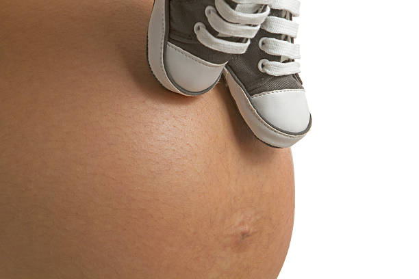 A pregnant belly with two shoes