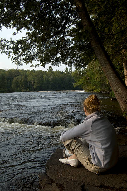 donna seduta a tahquamenon falls state park - waterfall zen like women meditating foto e immagini stock