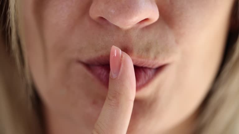 A woman puts a finger to her lips, slowmotion