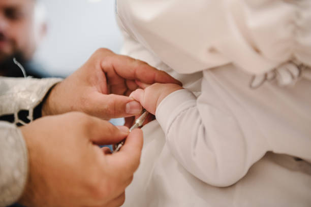 Baptism ceremony of a baby. Closeup of tiny baby hand, the sacrament of baptism. Godfather holds the child in his arms. Priest and godfather stretch their hands to child legs. Temple, Orthodoxy. ceremonia de bautizo de un bebé. primer plano de la pequeña mano de un bebé, el sacramento del bautismo. el padrino sostiene al niño en sus brazos. el sacerdote y el padrino estiran sus manos sobre las piernas de los niños. templo, ortodoxia.