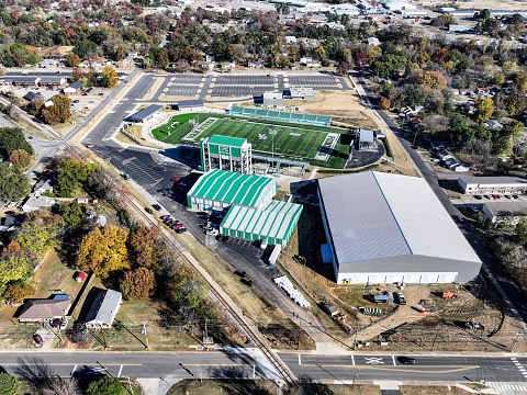 Van Buren, United States – November 13, 2023: A football field on a college campus in the process of being built in a bustling industrial area
