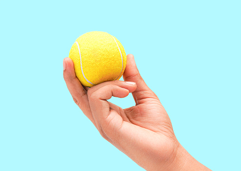 A Male Hand Holding Shiny Bright Tennis Ball Closeup Photo Isolated On Blue Background