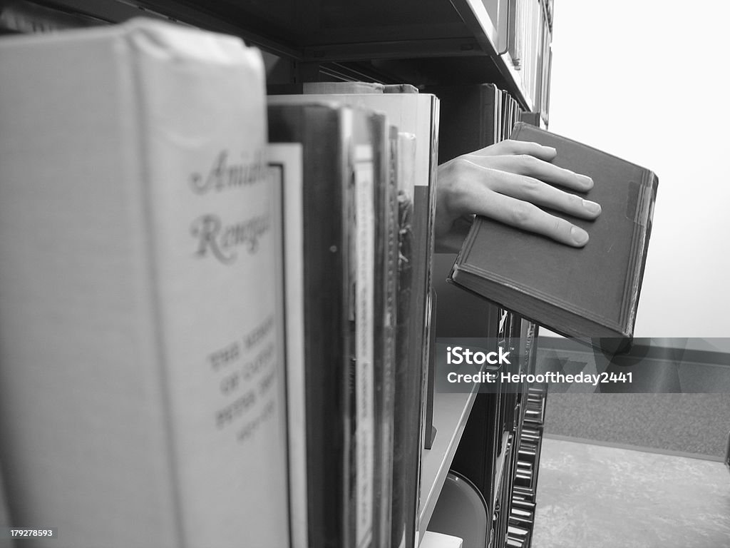 Helping Hand Lending a book to a passerby in a library aisle. Assistance Stock Photo