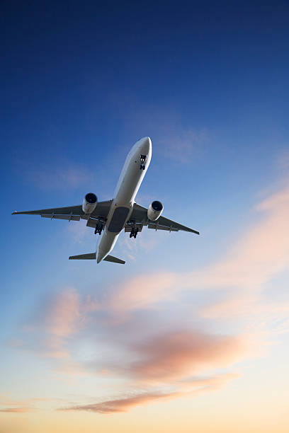 ジェットを着陸飛行機の夕暮れの空の明るいブルーオレンジ垂直 - landing sunset airplane flying ストックフォトと画像