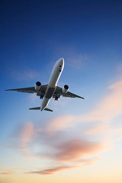 реактивный самолета посадку с яркие закат небо синий оранжевый вертикальные - air travel фотографии стоковые фото и изображения