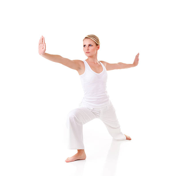Young woman posing in warriors pose while doing yoga stock photo
