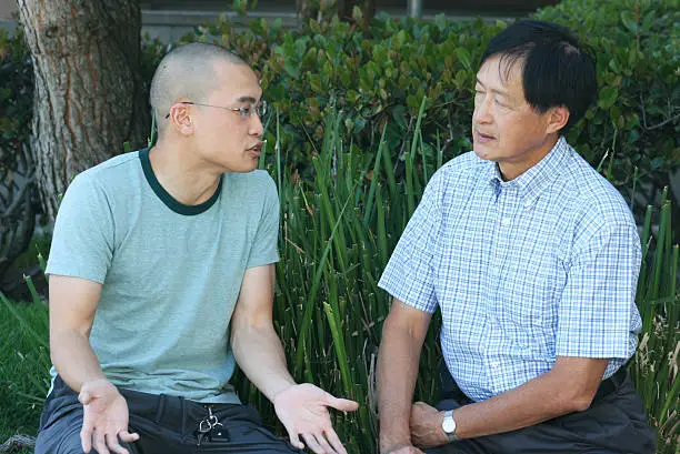 Photo of Father and son talking in a garden