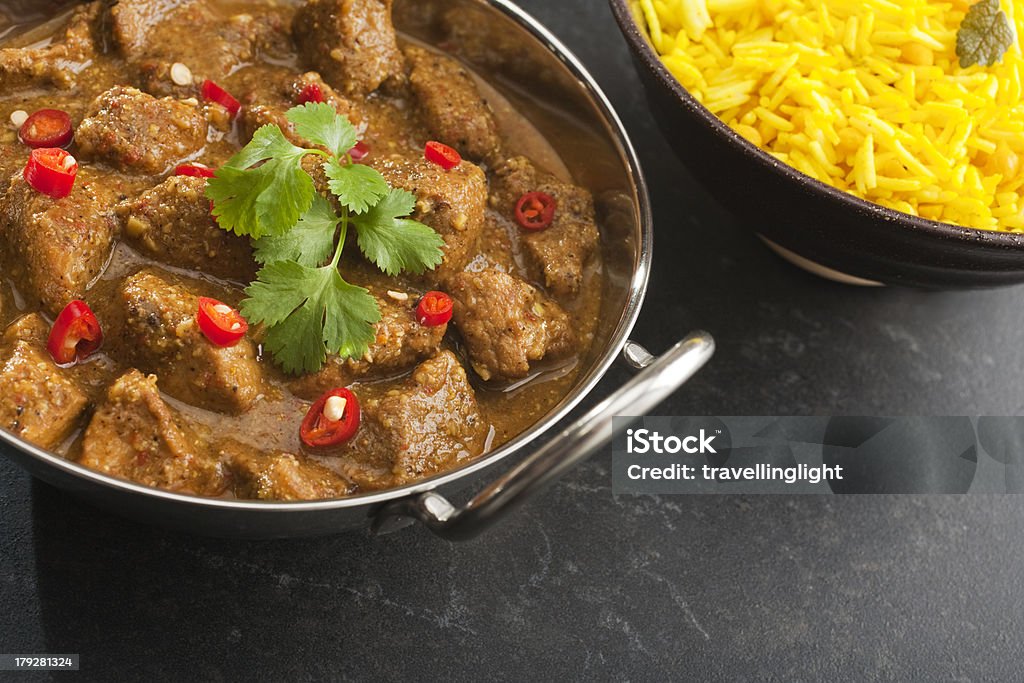 Indian Curry Meal Cuisine Meat Pork Vindaloo Balti Lemon Rice "A balti dish or steel karahi with Pork Vindaloo, a hot Indian curry garnished with red chili and coriander, with a side dish of basmati rice. More curry" Balti Dish Stock Photo