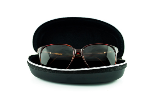 Brown sunglasses in black case isolated on white - eyeglasses in box